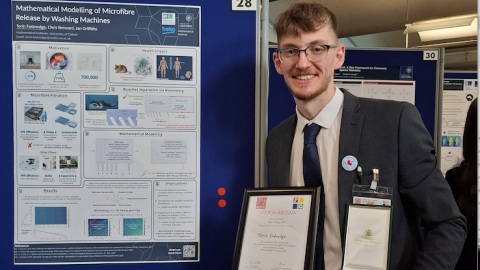 Photo of Torin with the medal by his poster