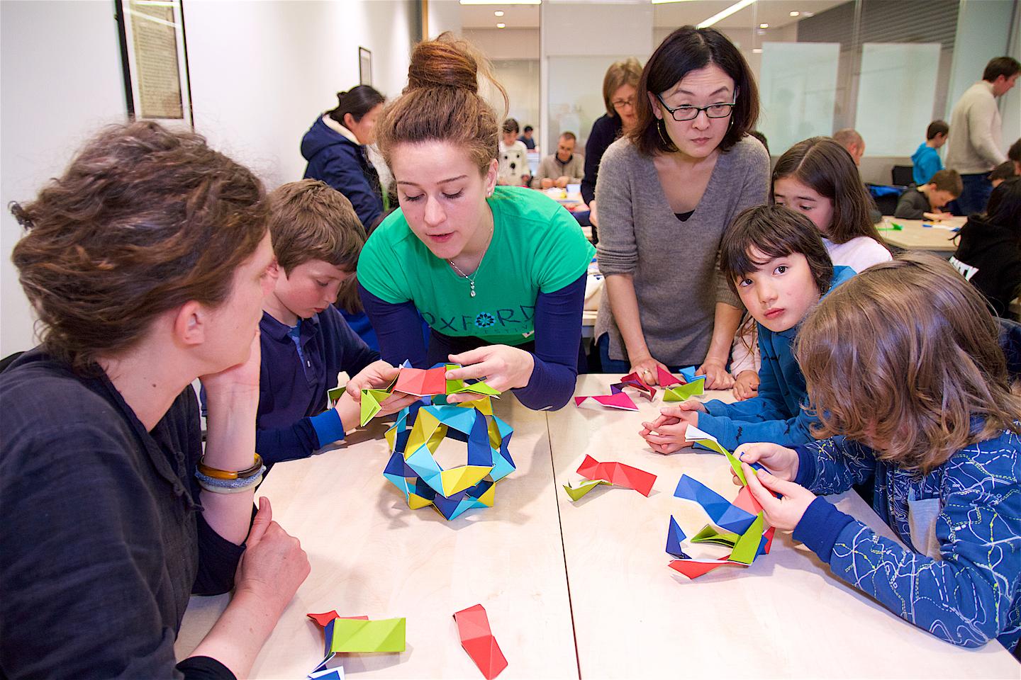 A volunteer helps participants with mathematical craft
