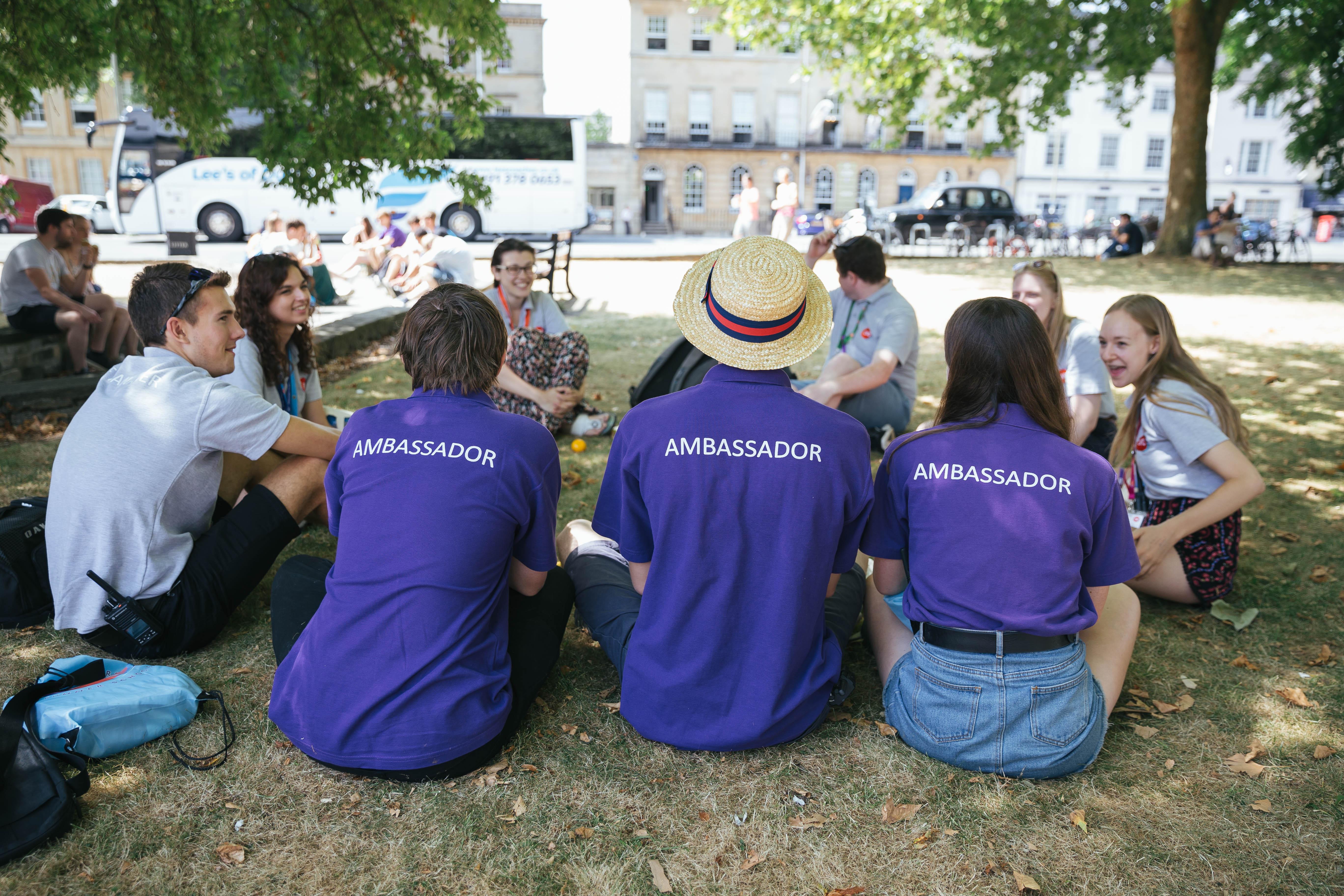 Three ambassadors in purple T-shirts with their back to the camera.