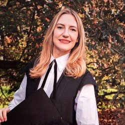 Woman wearing Oxford subfusc standing in a garden