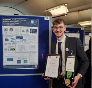 Photo of Torin with the medal by his poster