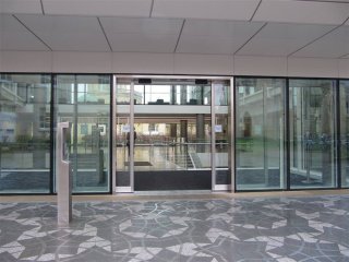 The front entrance of the AW building, with glass walls, sliding doors, and the Penrose Paving below The front entrance of the AW building, with glass walls, sliding doors, and the Penrose Paving below