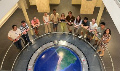 Students stand in a semicircle around a model globe, looking up at the camera