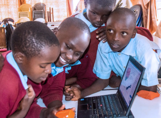 School children cluster around a computer 