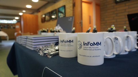 table full of InFoMM CDT mugs and conference paraphernalia